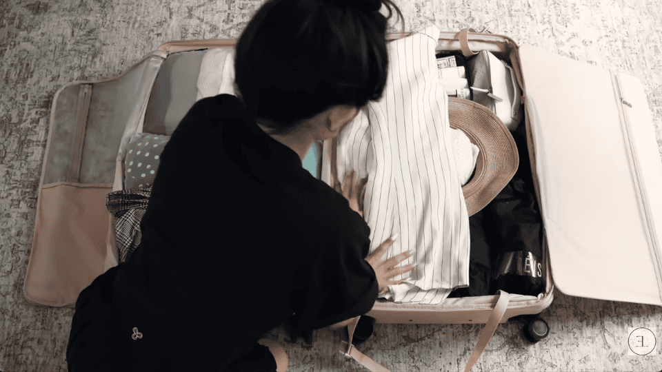 adding final flat layers of clothing in a suitcase to complete how to pack a suitcase efficiently
