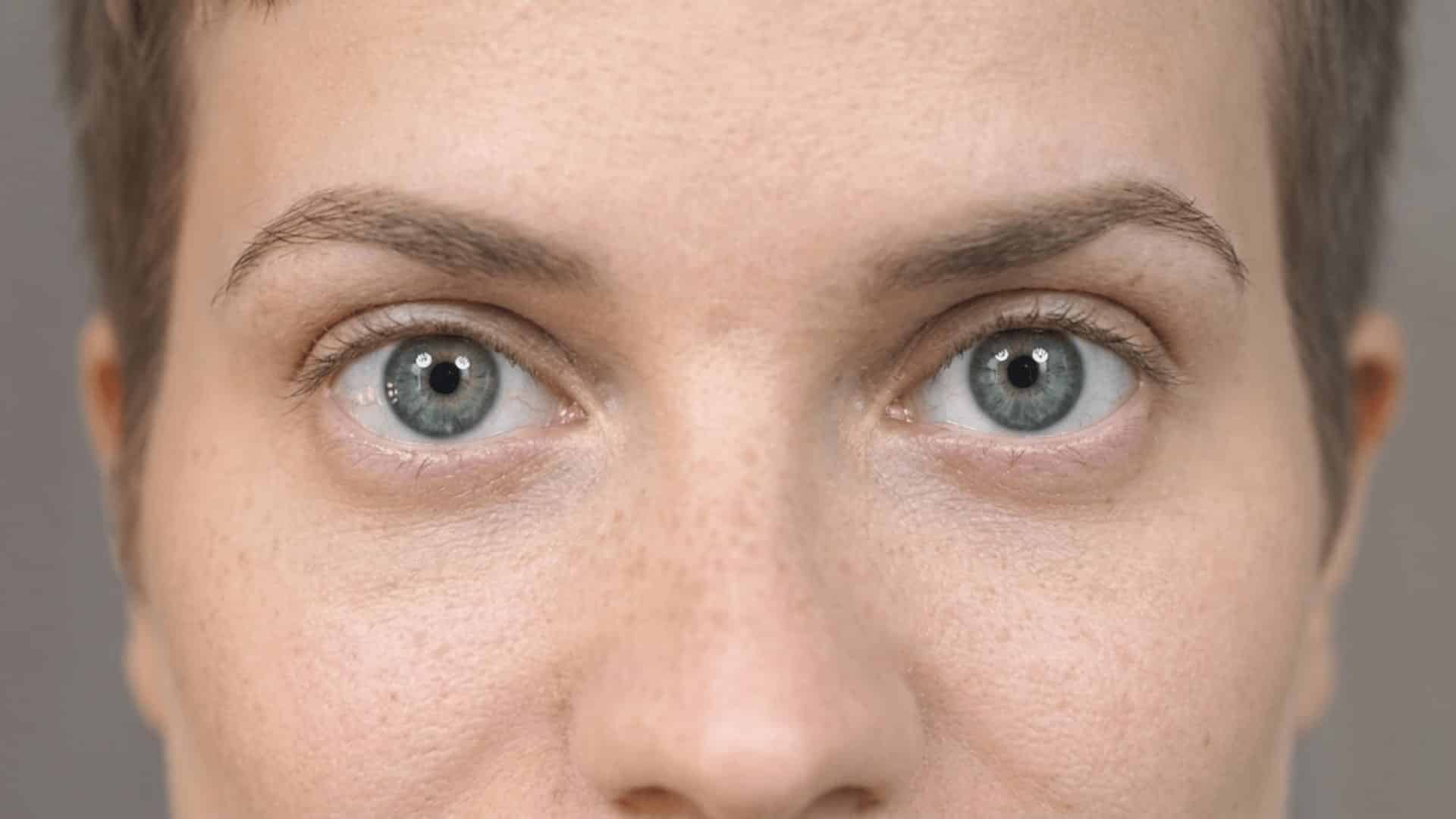 close-up of a caucasian woman's round blue eyes with freckled skin and short hair in 169 ratio.