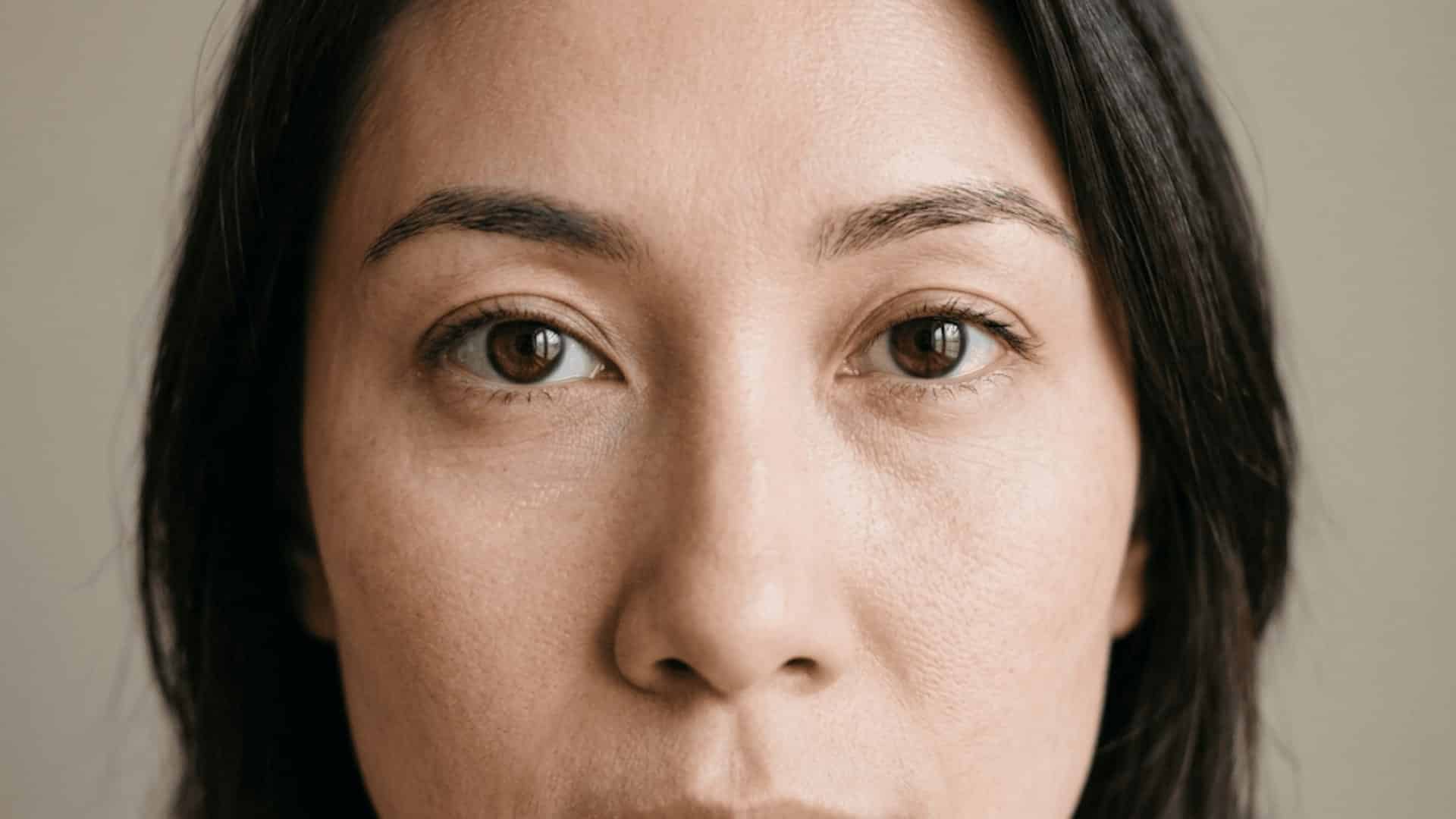 close-up of a woman with almond-shaped brown eyes, neutral expression, and soft natural lighting.
