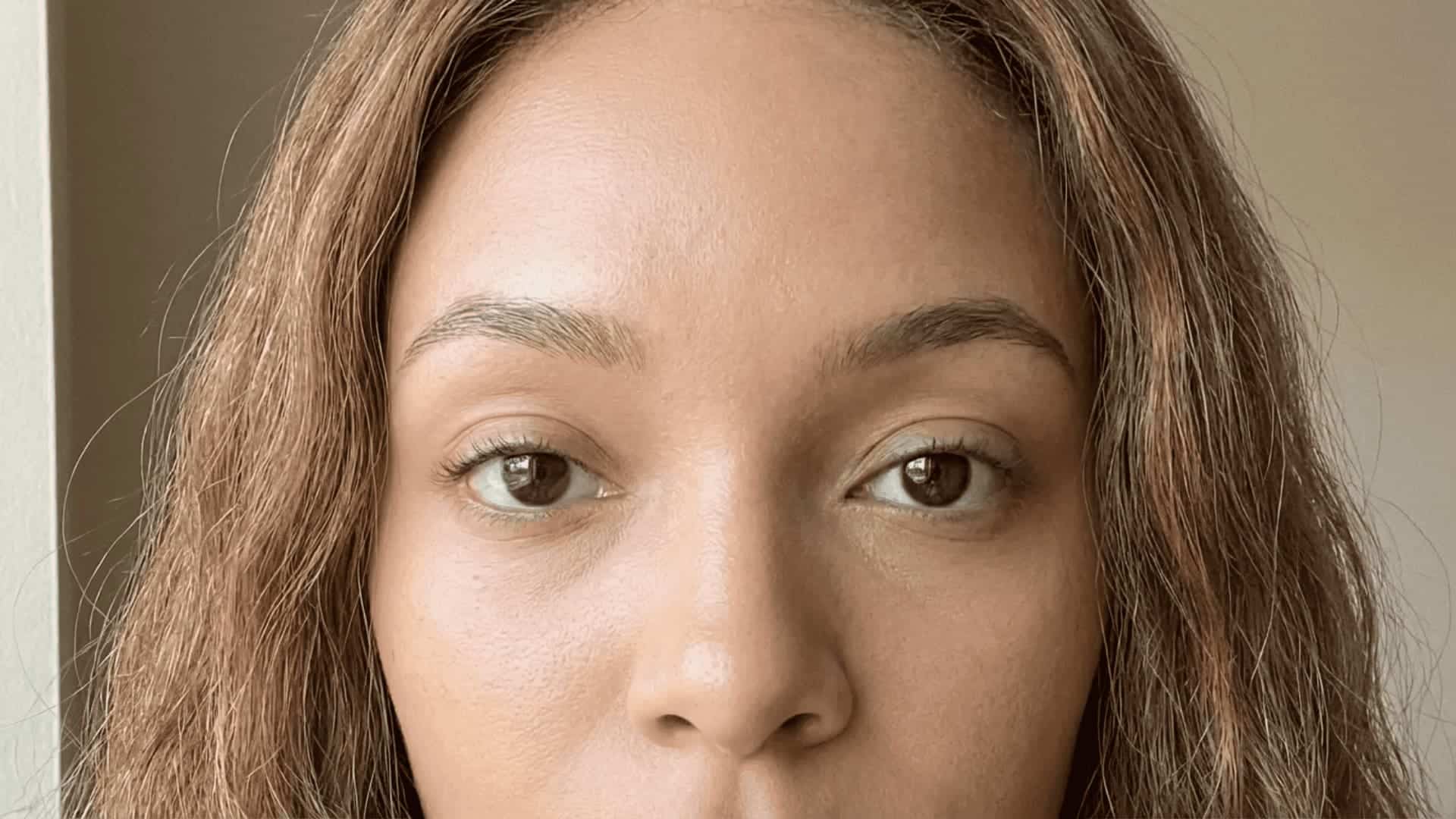 close-up of a woman with warm skin tones, visible natural texture, brown eyes, and realistic stray hair strands