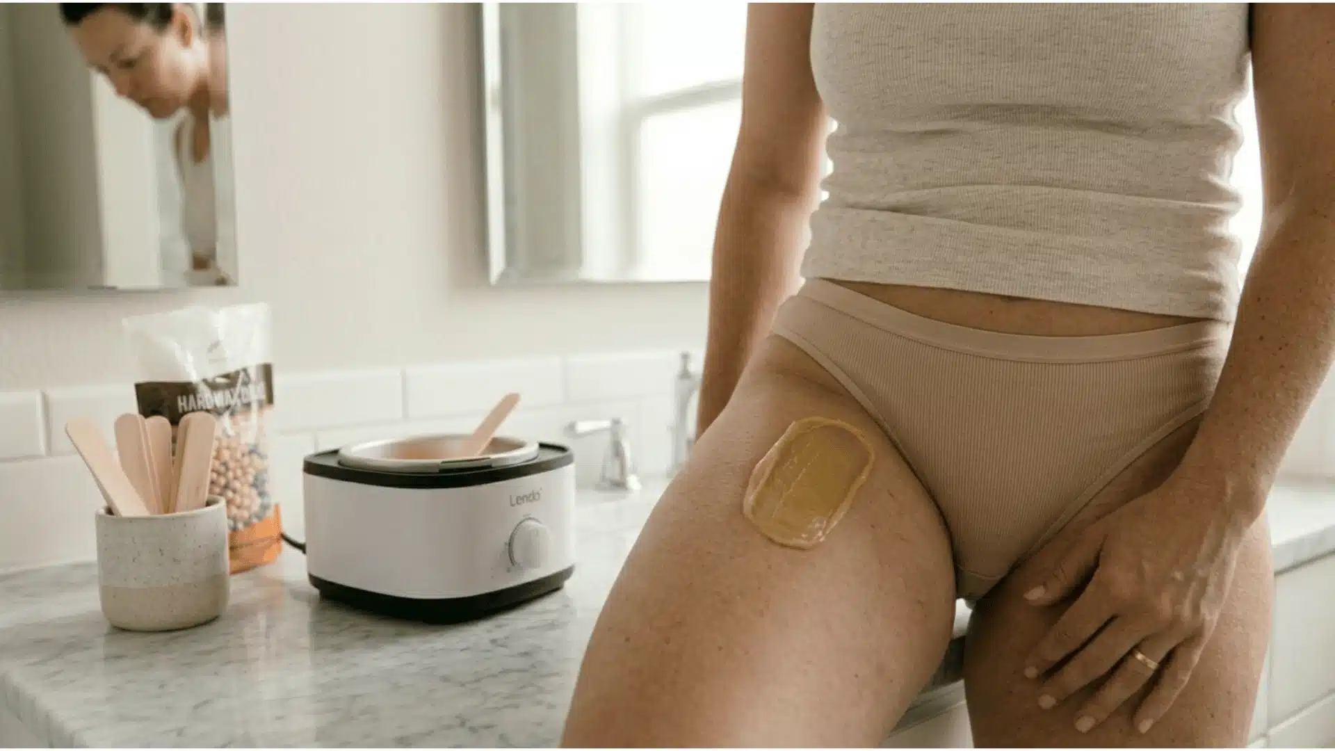 close-up of applied hard wax strip setting on the bikini line area, person gently touching the wax to check firmness