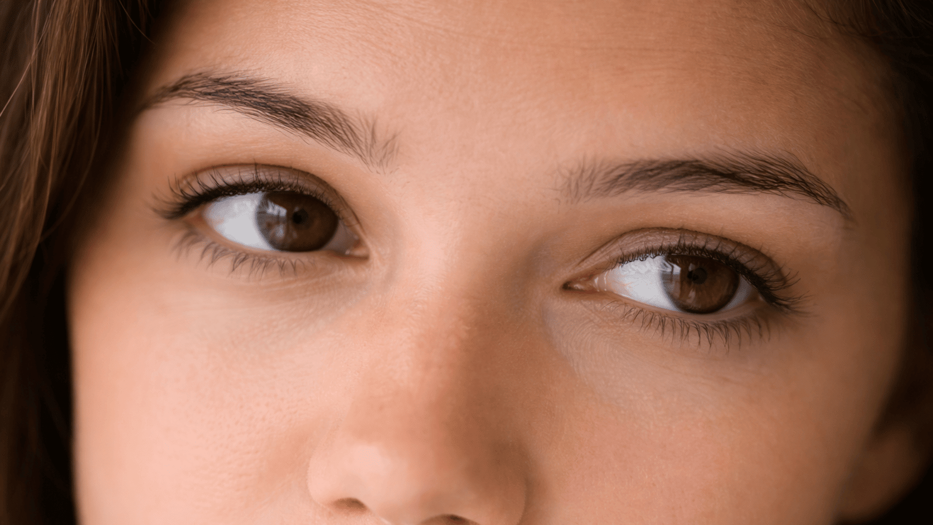 close-up of downturned brown eyes with natural skin texture and soft warm lighting on the face