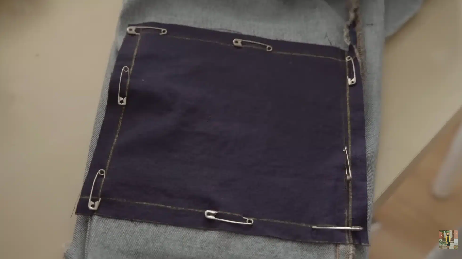 denim patch pinned inside torn jeans with safety pins, preparing fabric for stitching to reinforce damaged denim area