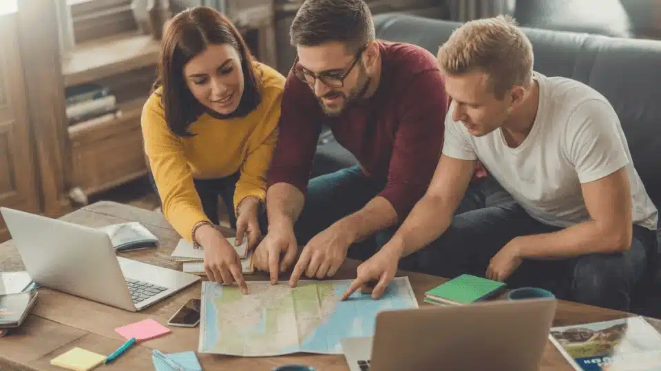 friends planning a future trip together using maps and laptops during a fun and creative hangout