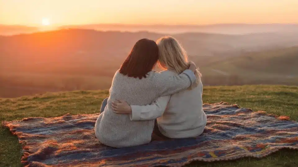 friends sitting on blankets watching the sunrise together during a calm and peaceful outdoor hangout