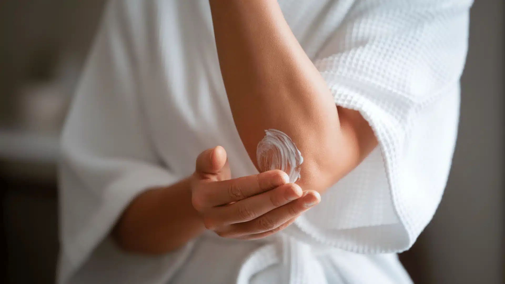 individual is applying a creamy substance, possibly a moisturizer or lotion, to their elbow