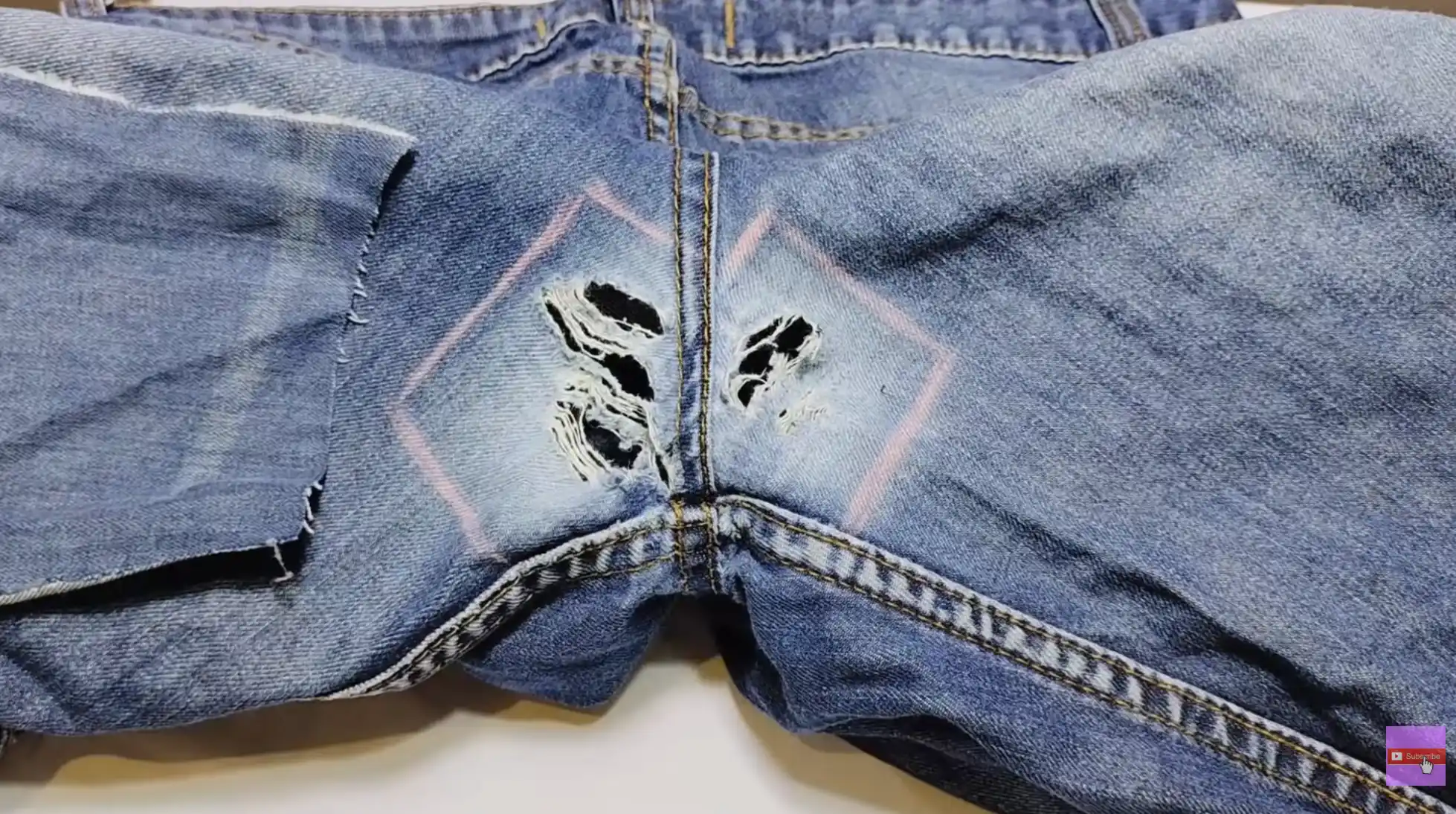 jeans crotch area with multiple tears outlined for repair, showing damaged denim fabric before patching