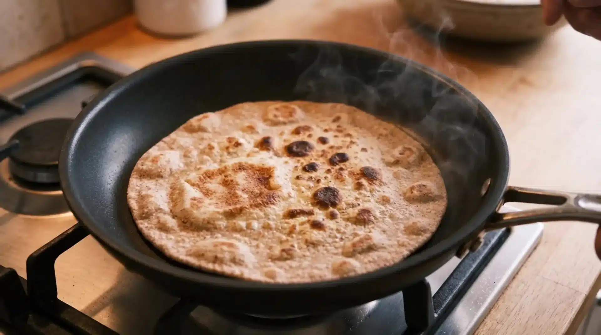 the image shows a flatbread cooking in a skillet, with steam rising as the bread turns golden brown