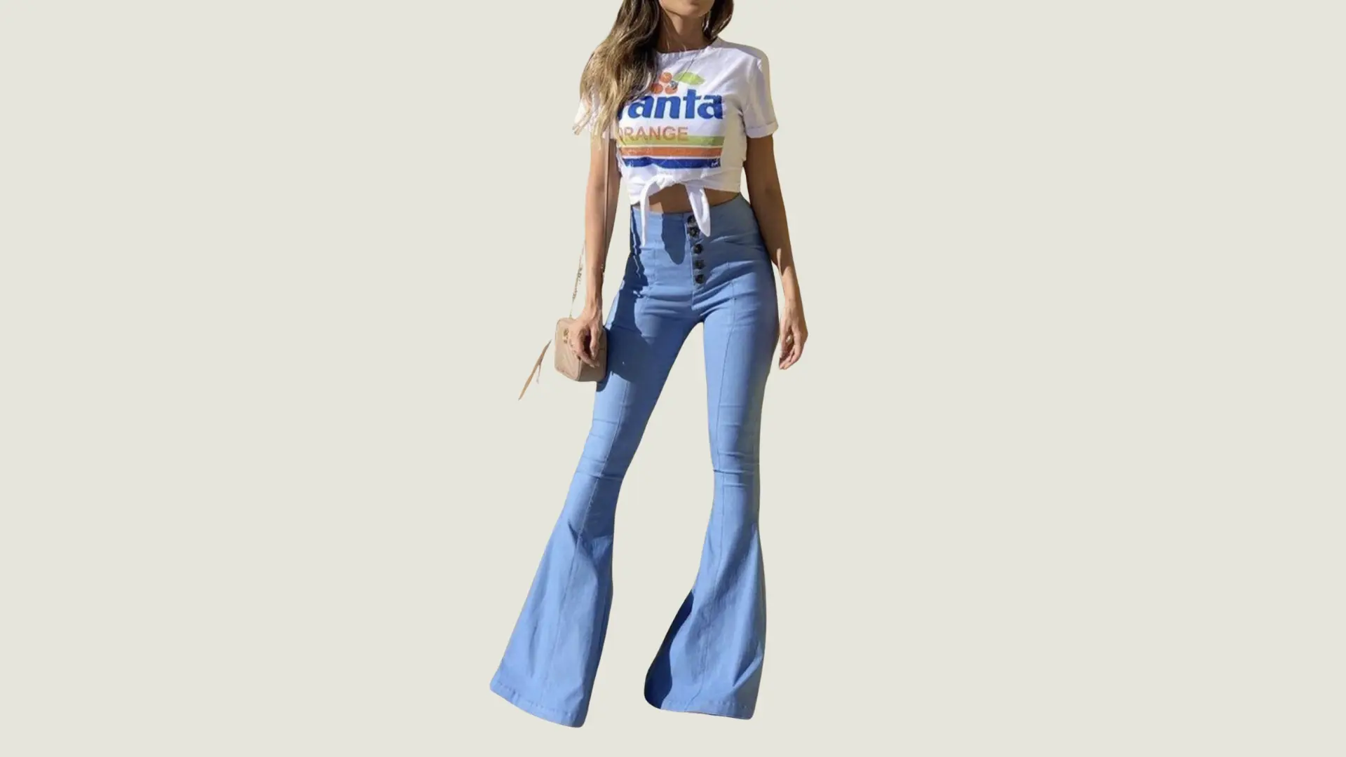woman in 90s style wearing a white graphic tee tied at the waist with light blue high-waisted flared denim jeans