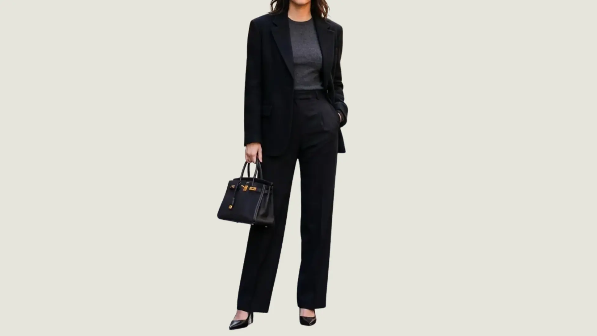 woman in a chic style wearing a black blazer over a charcoal top with black trousers and holding a black handbag