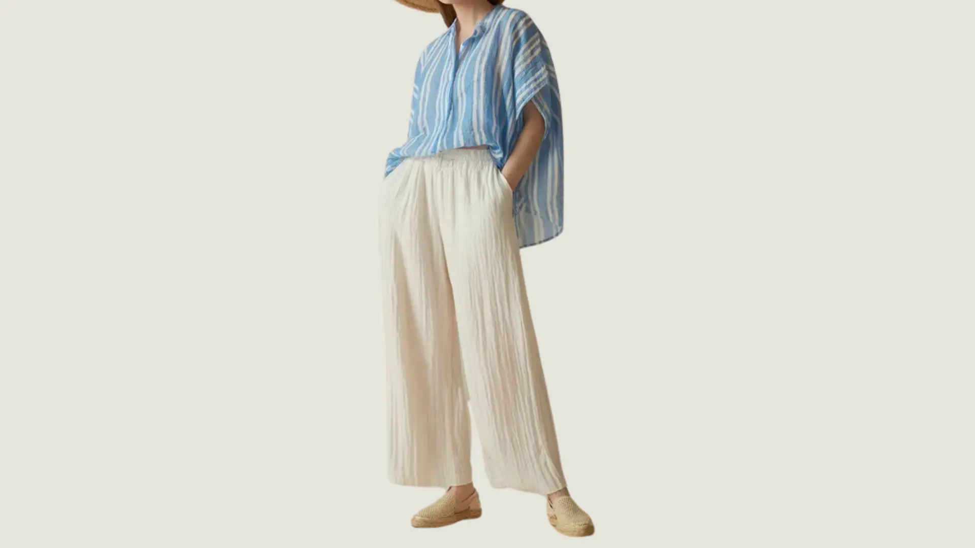 woman in a coastal style wearing a blue and white striped shirt with loose white linen trousers and espadrilles