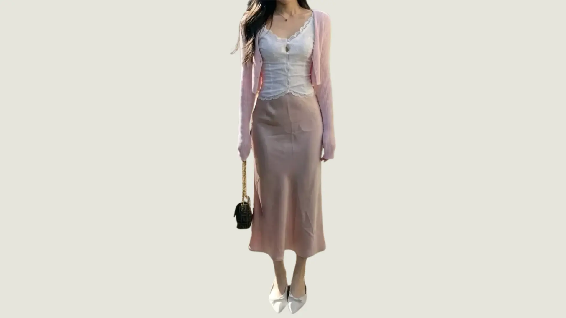 woman in a feminine style wearing a pink cardigan over a white lace camisole and a pink silk midi skirt with white flats