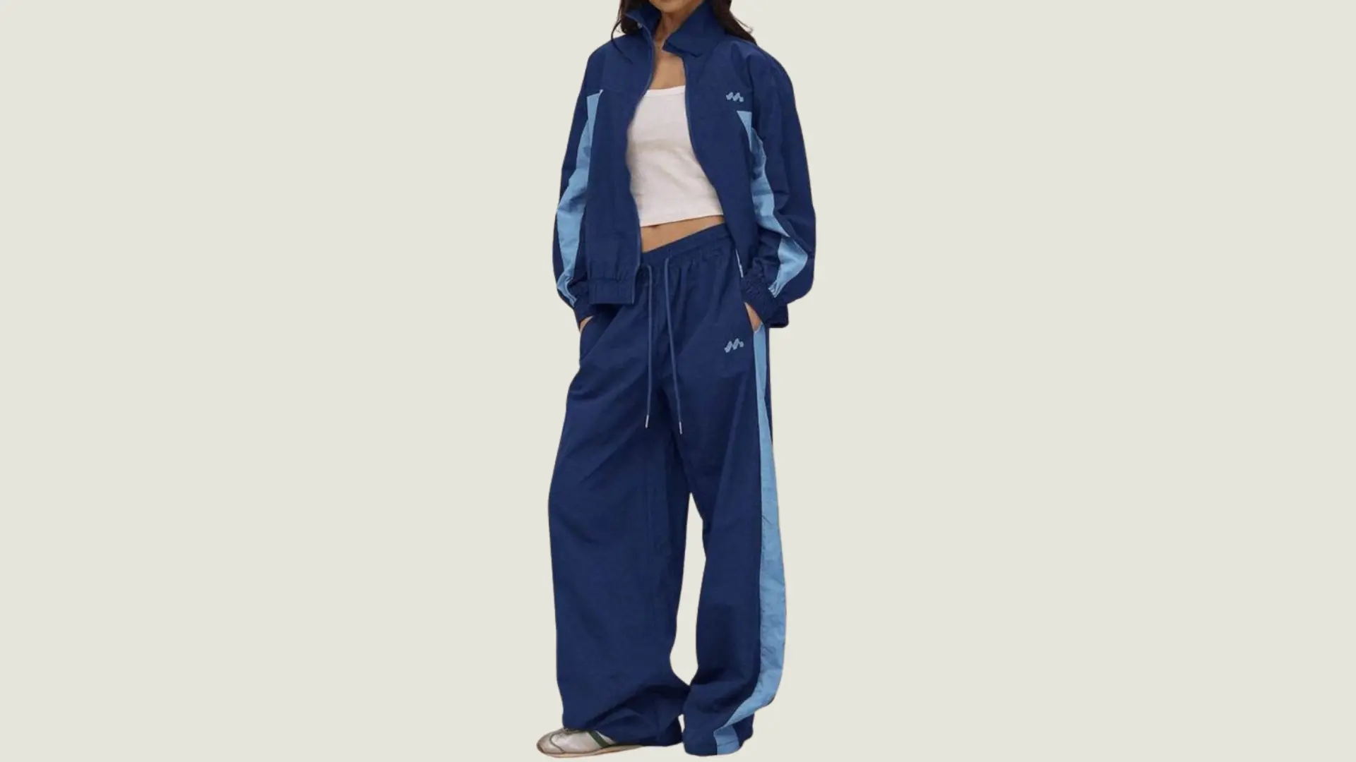 woman in a sporty style wearing a blue and light blue tracksuit over a white crop top with sneakers