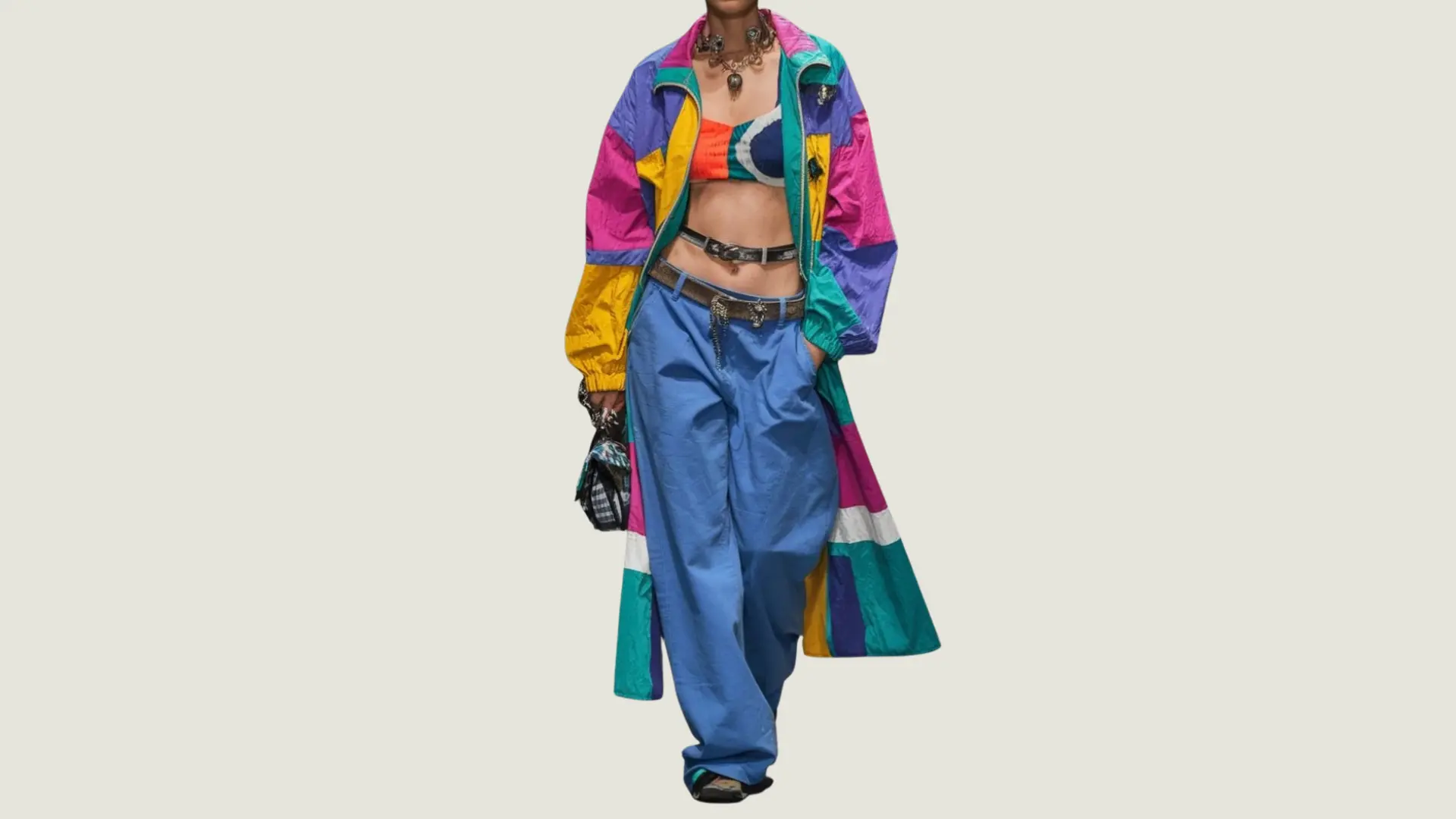 woman in artsy_creative style wearing a long colorful patchwork coat over a bikini top and blue baggy trousers