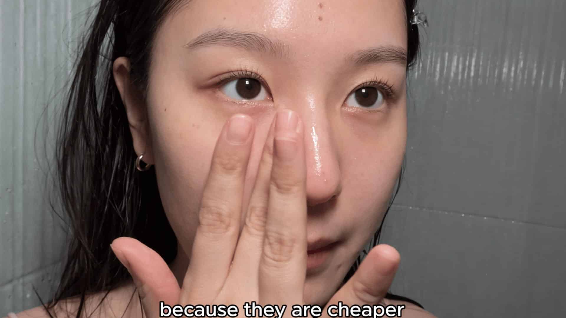 young woman with wet hair applying skincare to her nose in bathroom close-up with dewy skin and tiled background