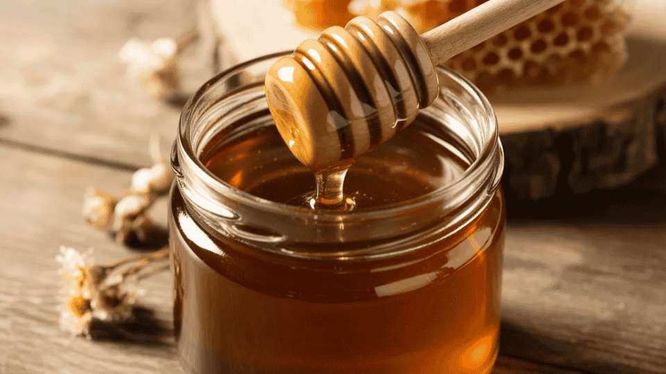 manuka honey in glass jar with wooden dipper for soothing red spots and calming irritated skin