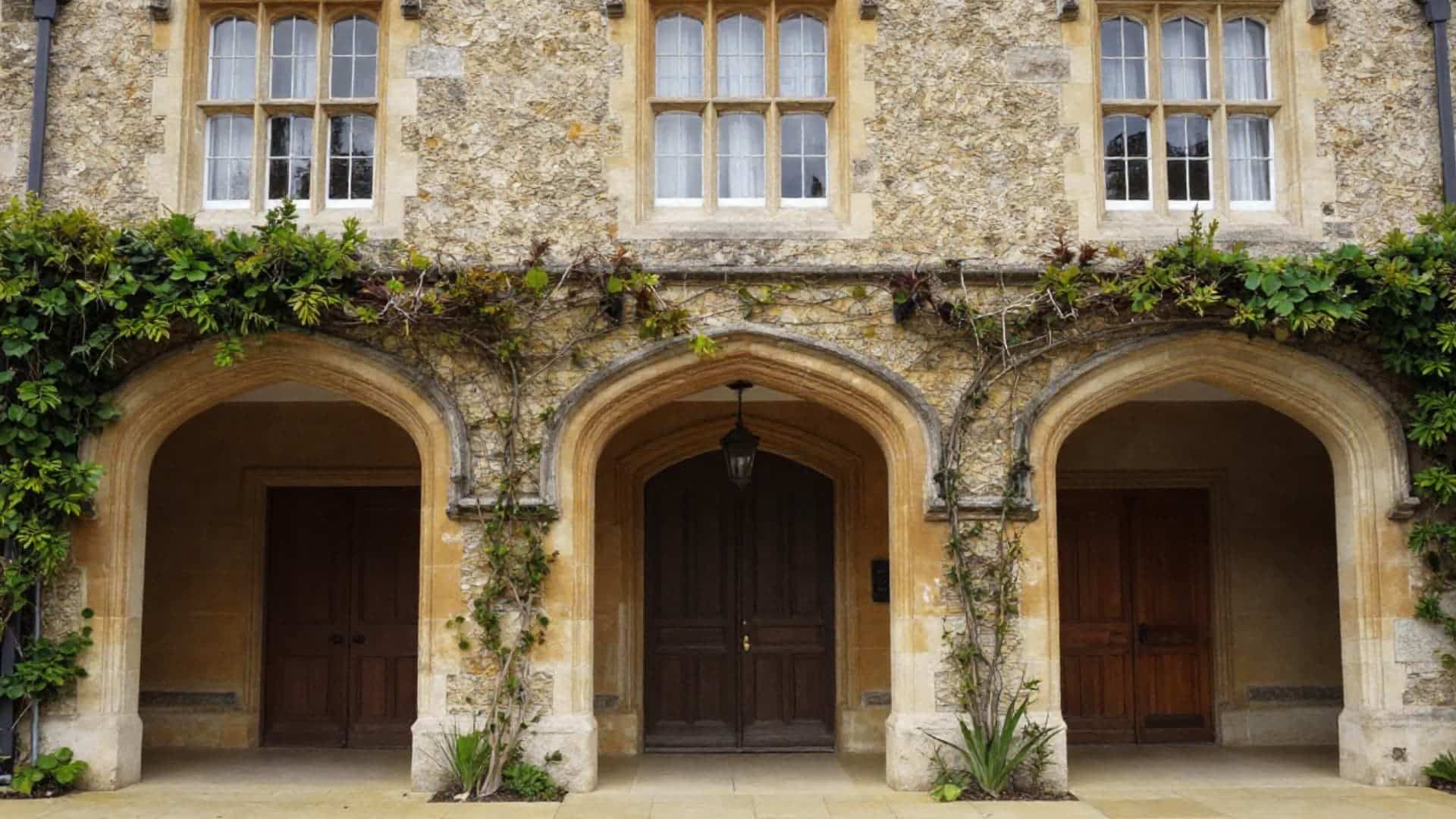 tudor house style arched doorways with heavy wooden doors stone surrounds and gothic inspired pointed arch shapes