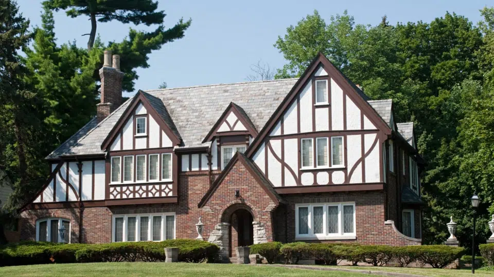 tudor house style exterior with brick walls white stucco panels dark timber framing steep roof and tall brick chimney