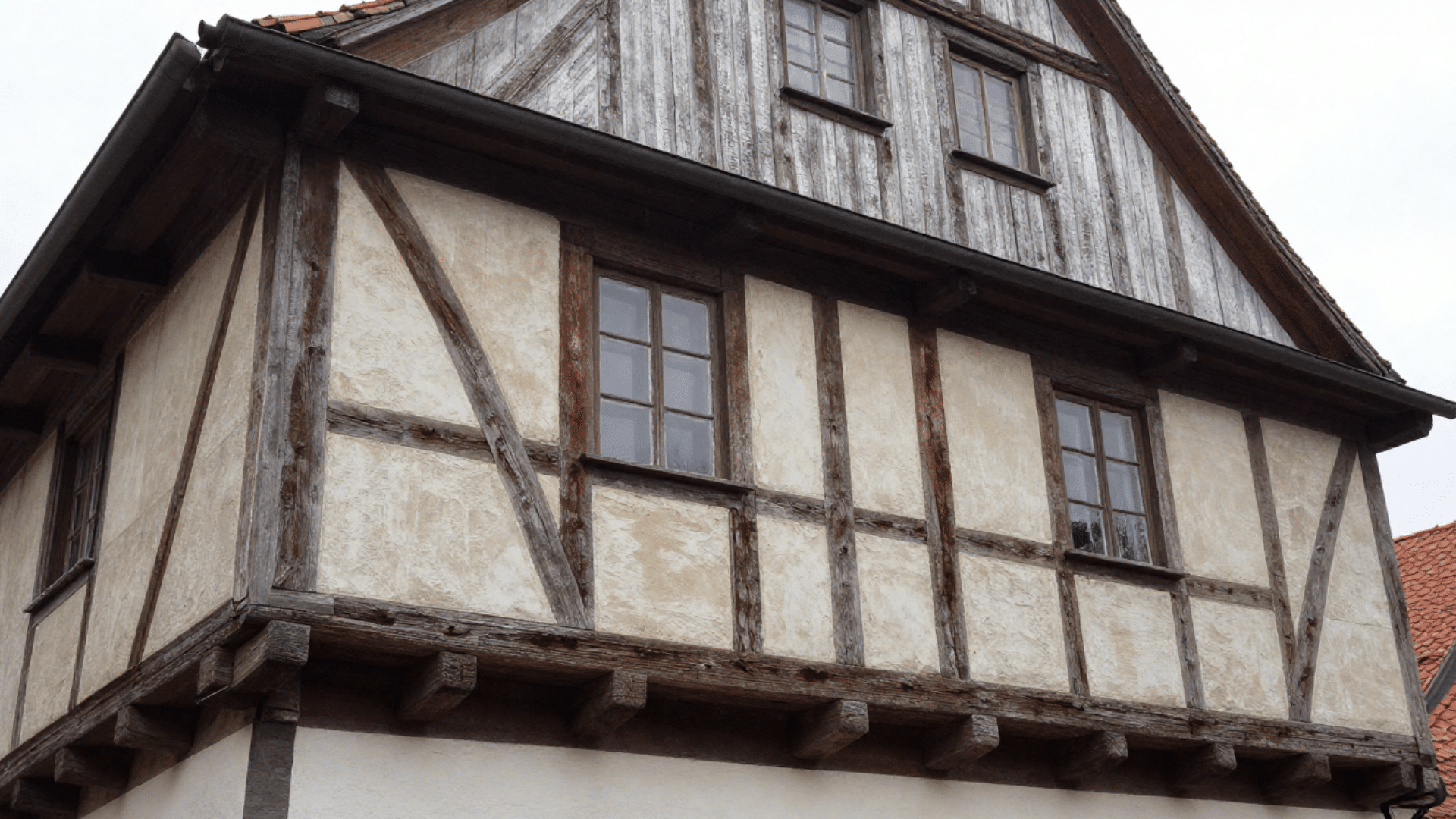 tudor house style half timber framing with exposed wooden beams triangular gables and decorative structural patterns on facade