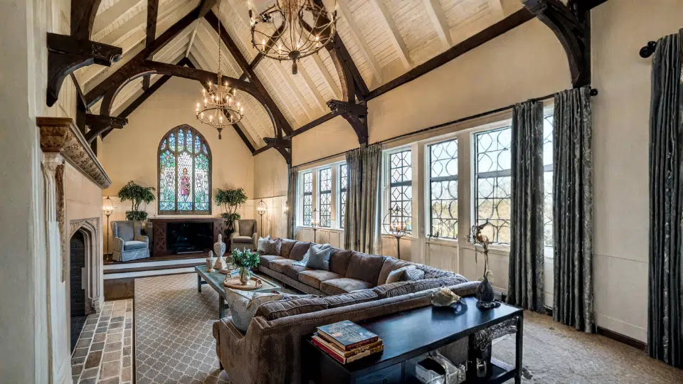 tudor house style interior with exposed wood beams vaulted ceiling leaded glass windows stone fireplace and large traditional living room