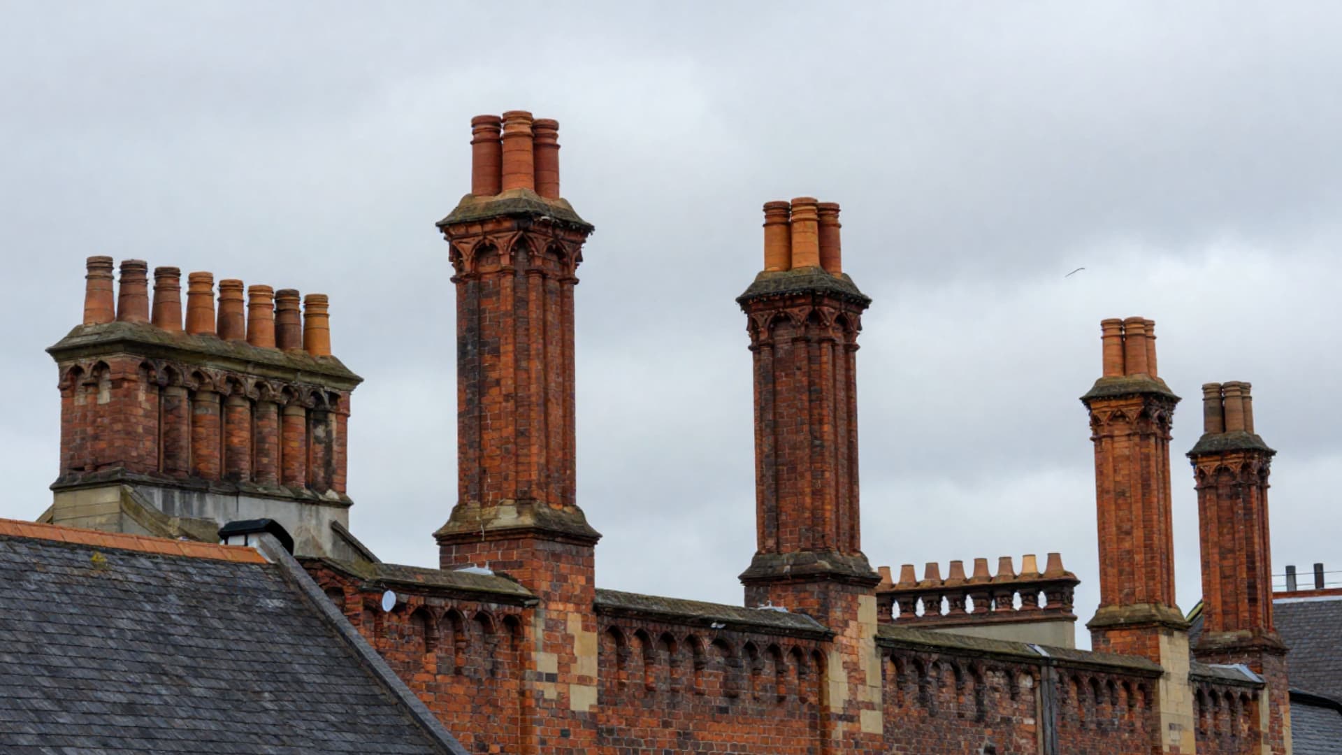 tudor house style tall decorative chimneys made of brick with patterned stacks ornate tops and clustered chimney designs on roof