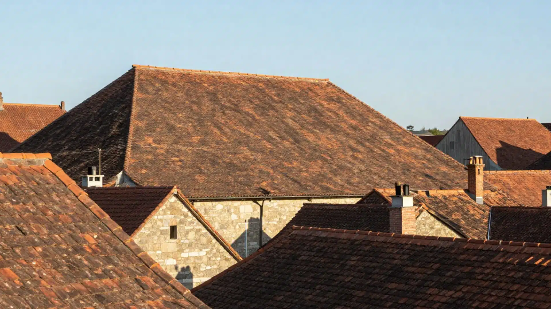 tudor style home with steeply pitched gable roofs layered rooflines timber framing and tall narrow dormers and chimneys