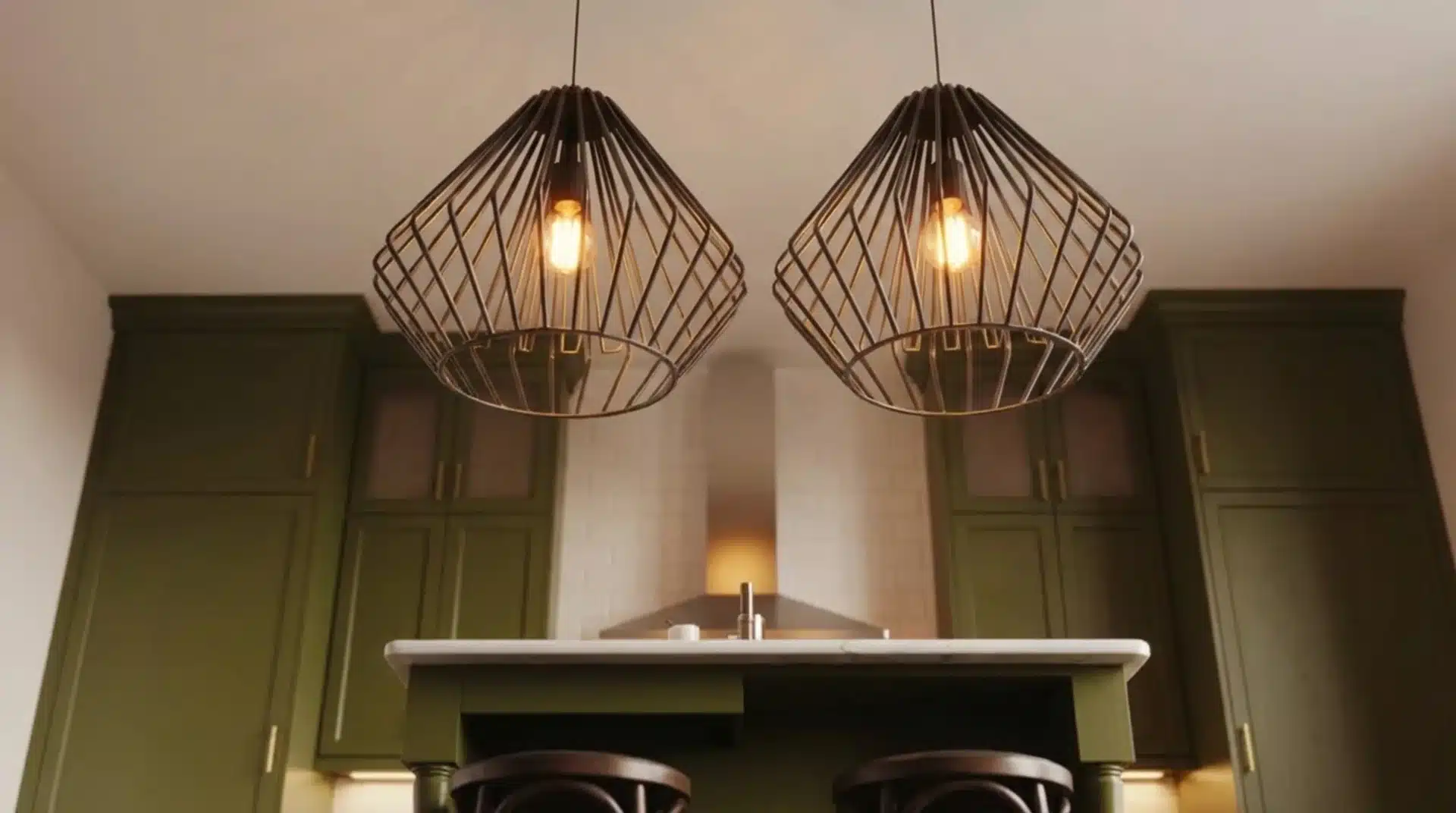 two large industrial pendant lights hanging over a kitchen island with dark green cabinetry and marble countertops