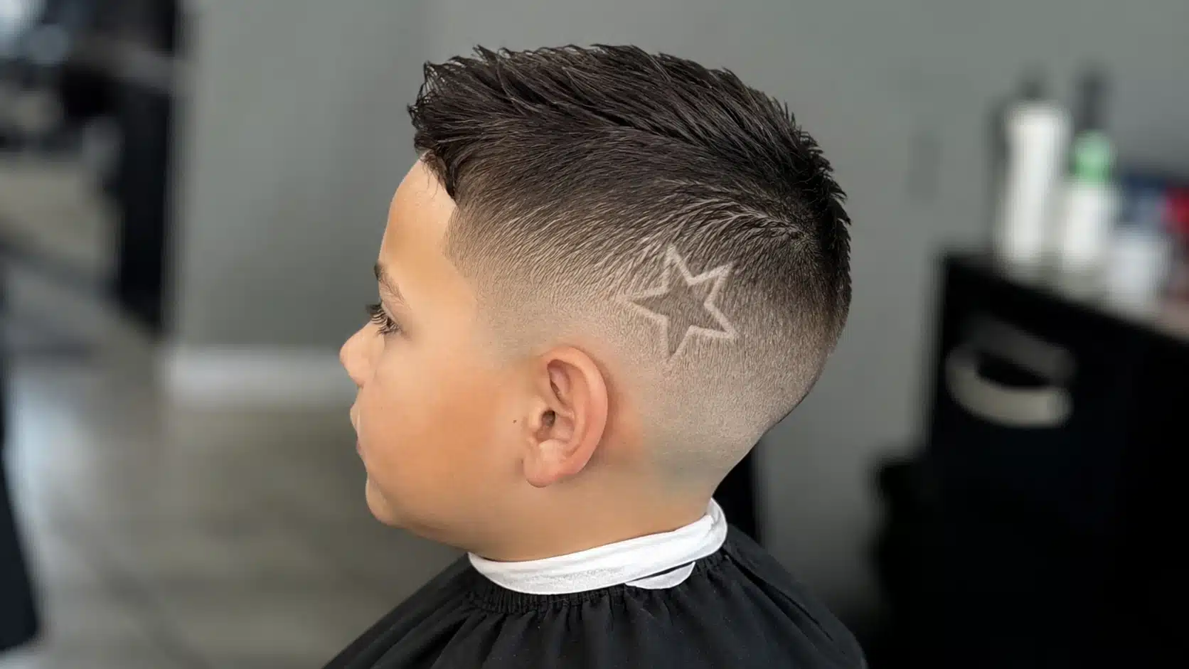 boys haircut with design featuring a small star shaved into the side of a fade