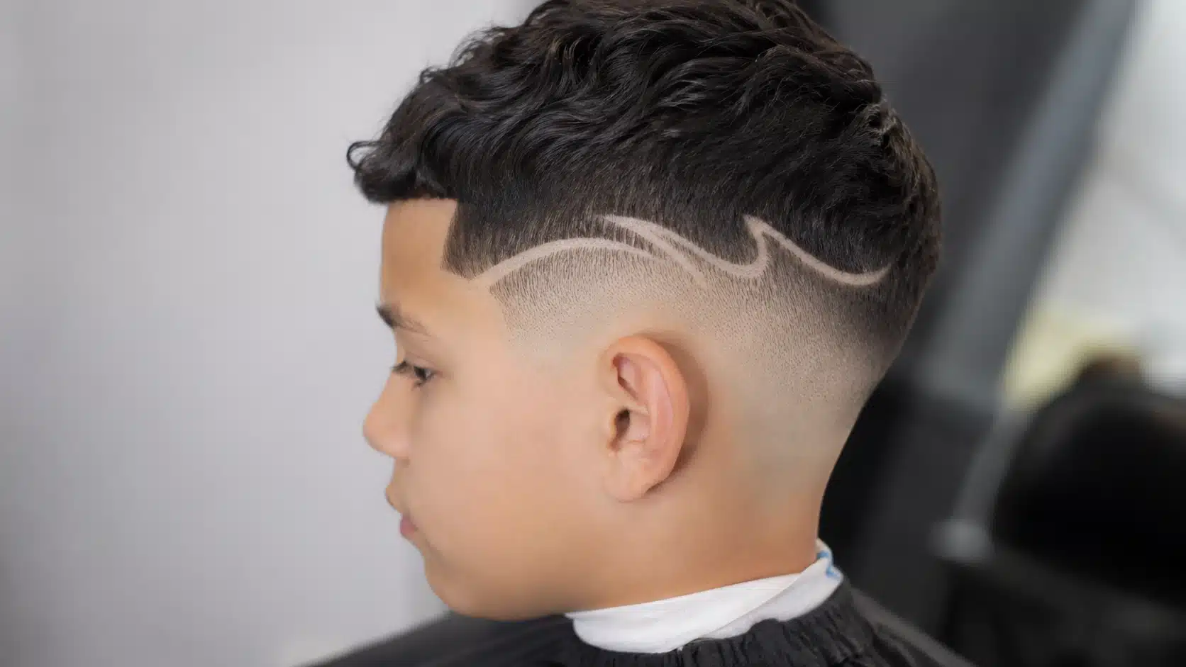 boys haircut with design featuring a soft wave line with curly or textured hair on top