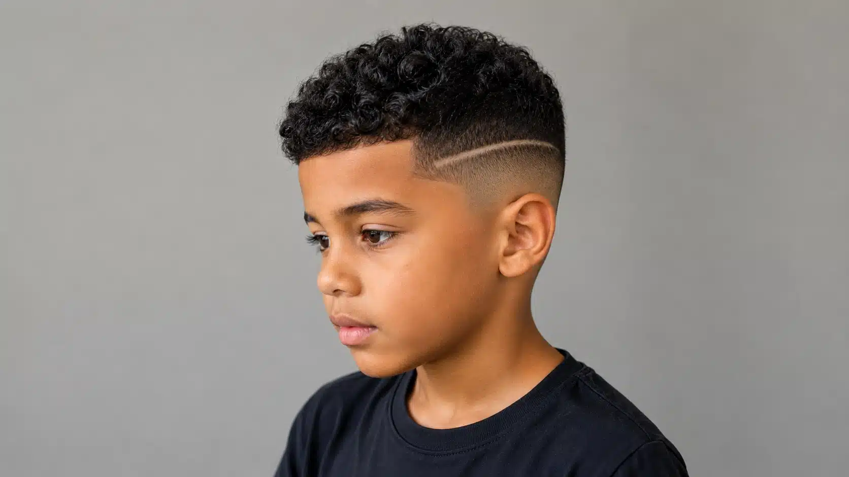 boys haircut with design featuring curly top hair with a clean shaved line in the fade
