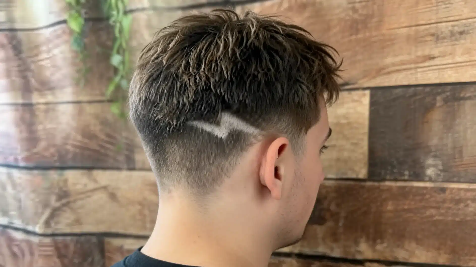 boys haircut with design showing a sharp lightning bolt shaved into a faded side cut