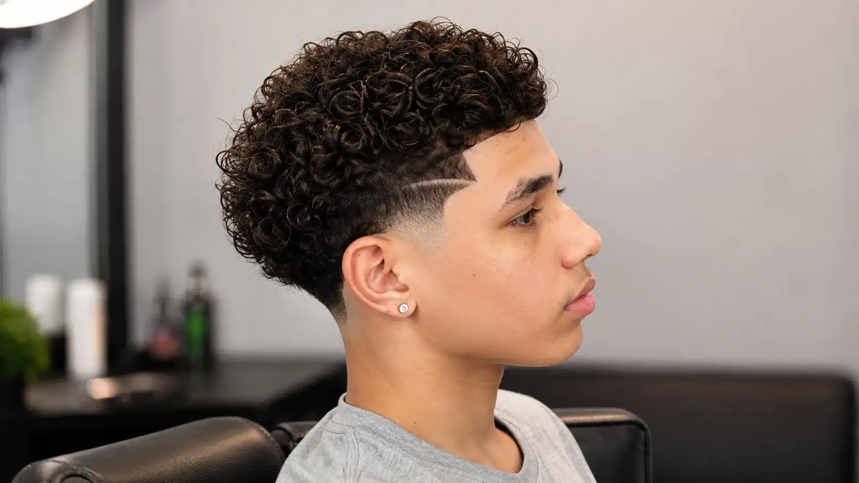 boys haircut with design showing coily top hair with a small taper design near the temple