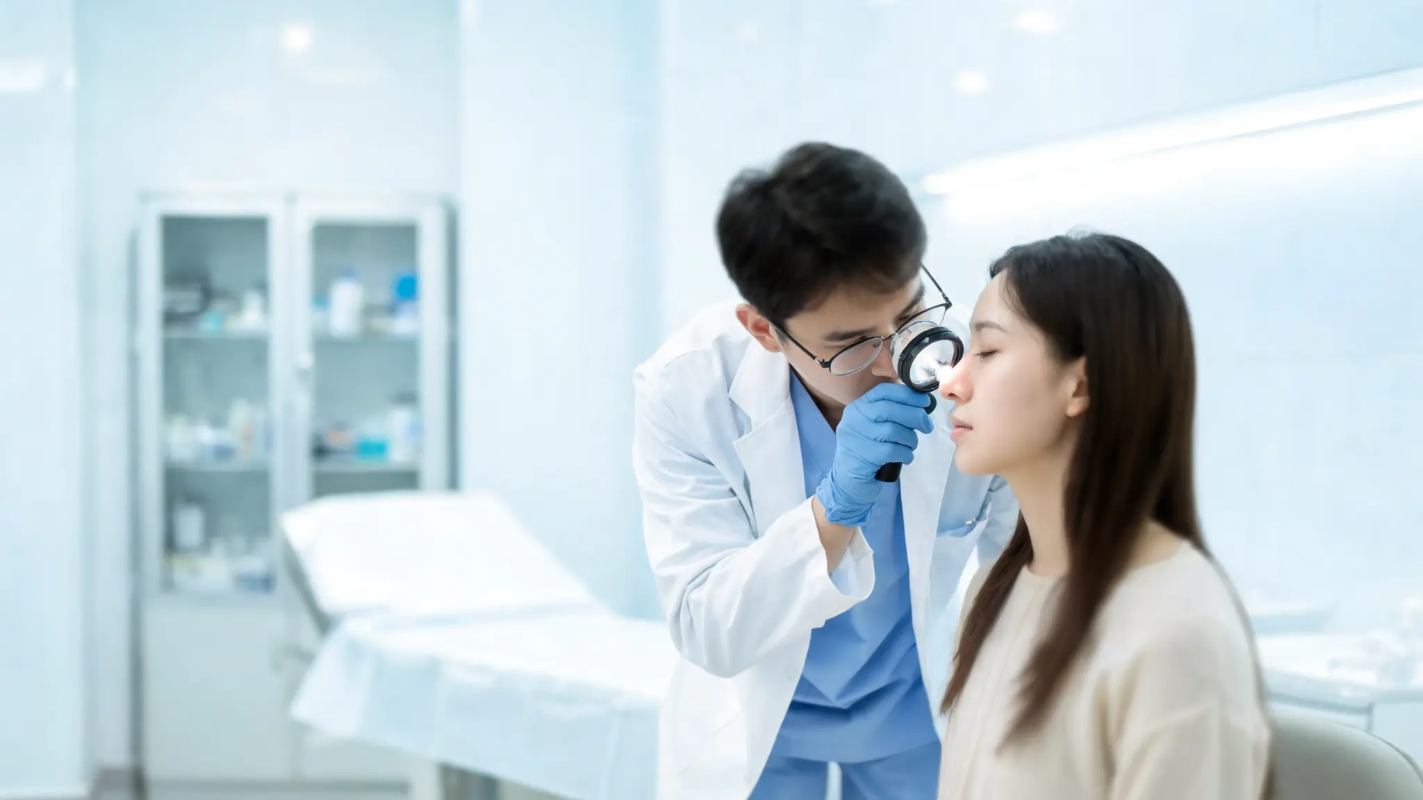 close up dermatology consultation where doctor examines patient nose for oily skin and skin condition analysis