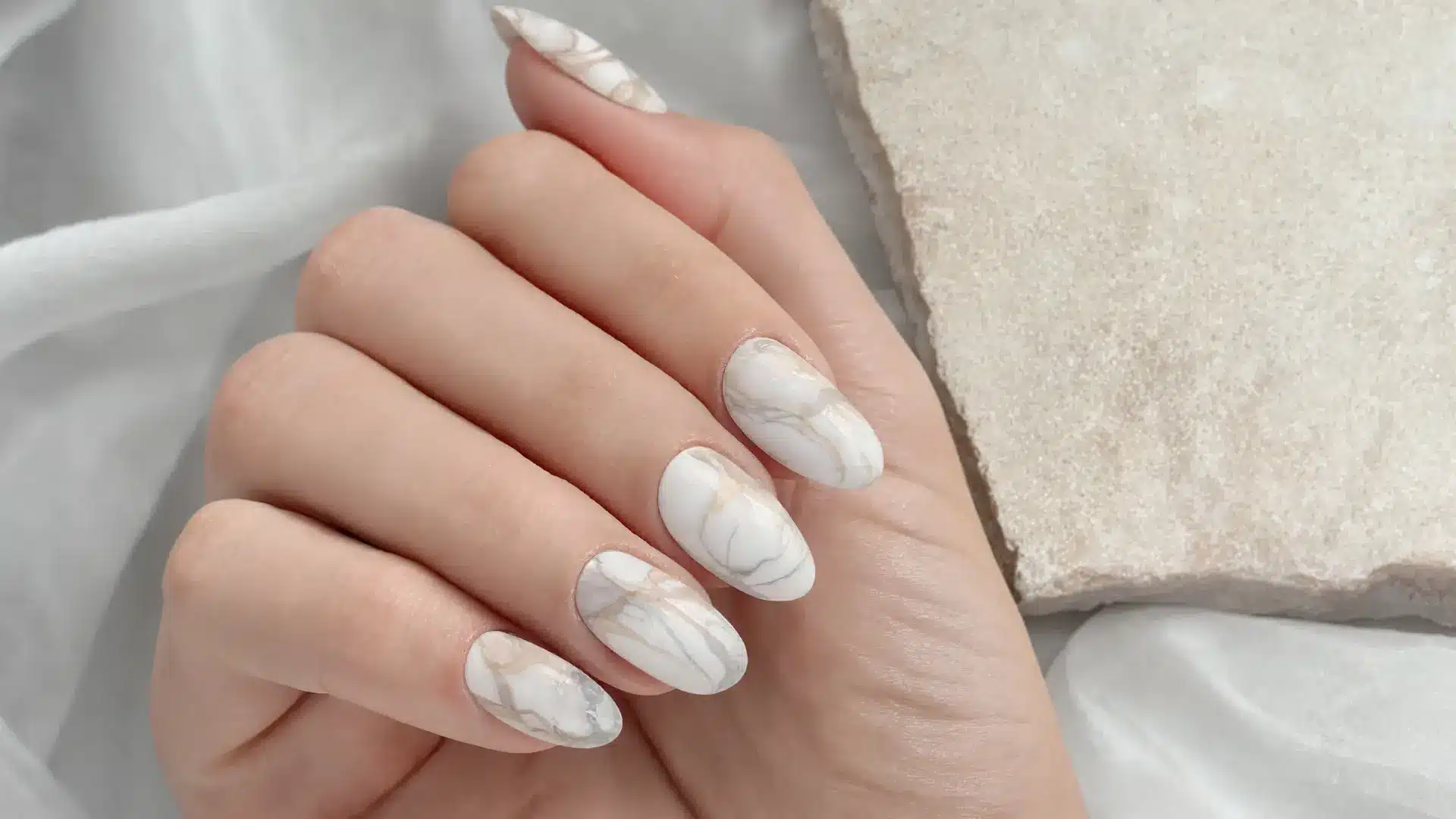 close up marble nails stone swirl pattern white grey beige tones almond coffin oval shapes luxury gel finish soft light
