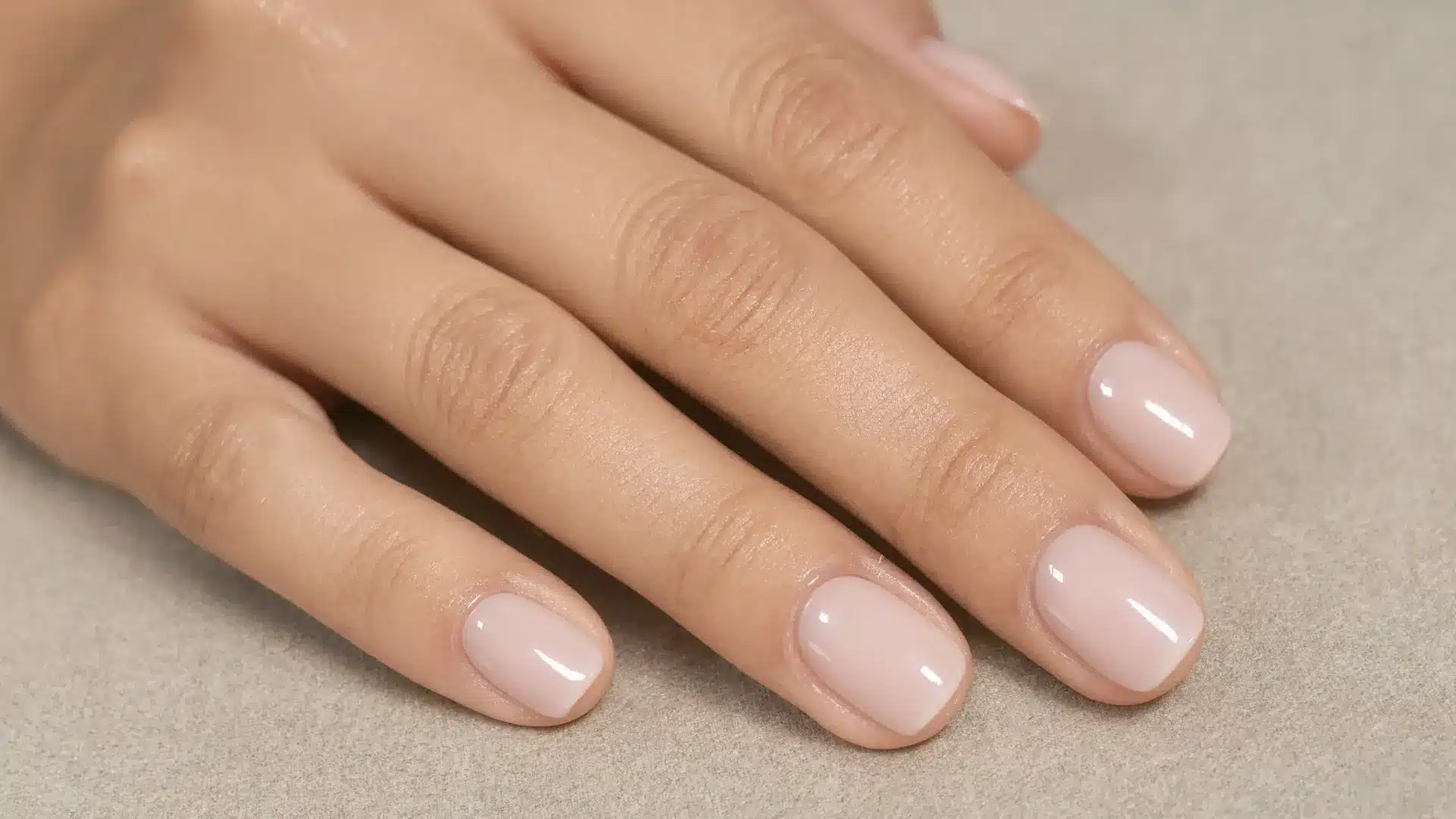 close up realistic nude gel overlay nails short almond shape sheer nude glossy finish