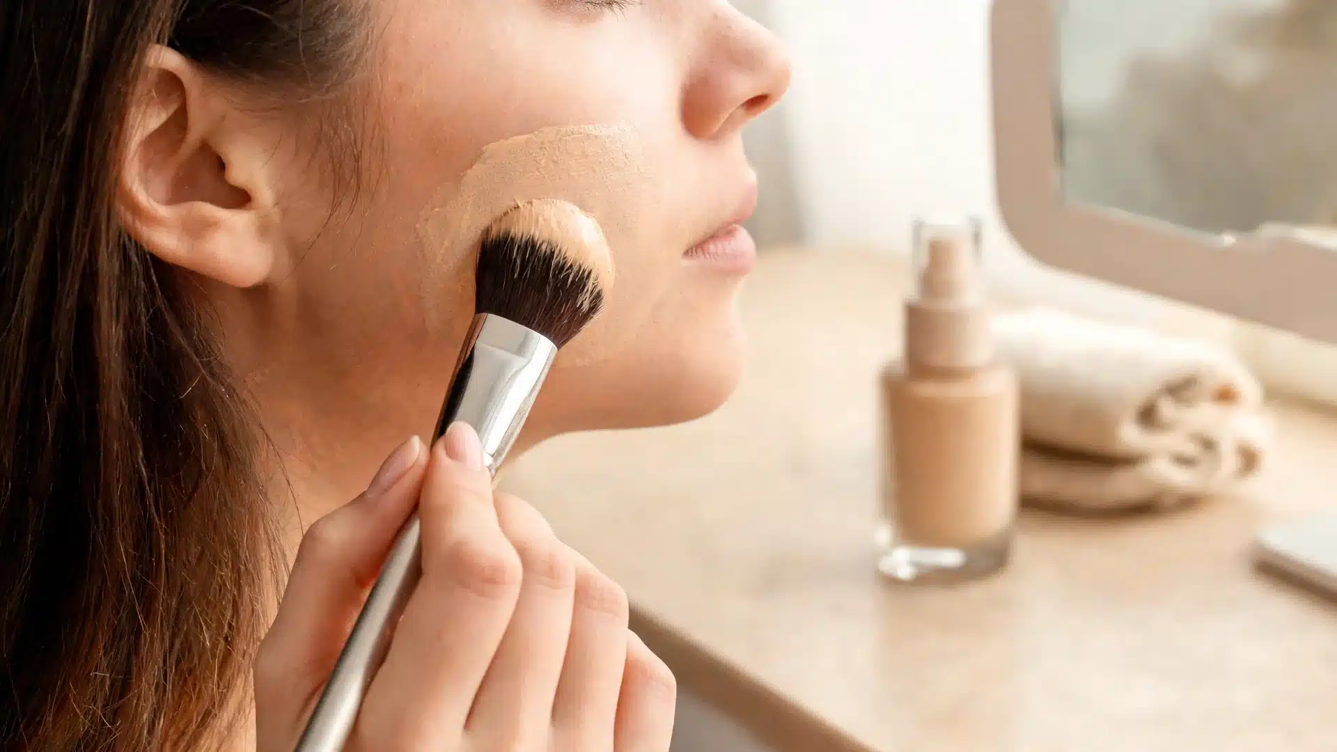 foundation brush vs sponge section showing a dense brush applying controlled coverage to the cheek