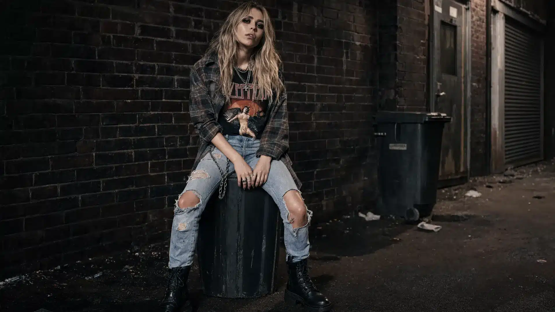 grunge aesthetic fashion photo with ripped jeans, flannel shirt, combat boots, and dark urban alley vibe