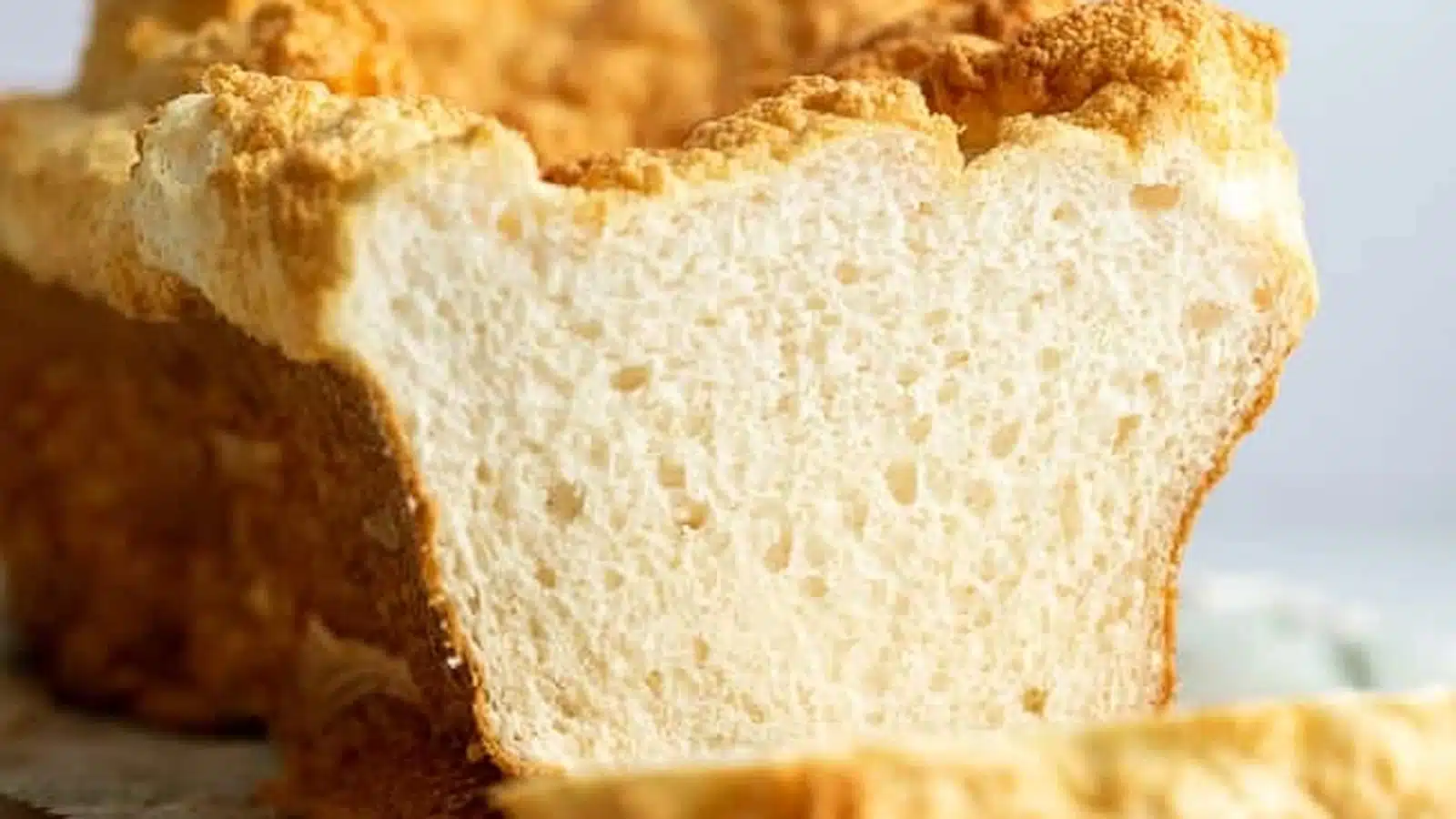 high protein egg white bread loaf sliced to reveal soft airy cloud like texture on wooden board with eggs in background natural light (3)