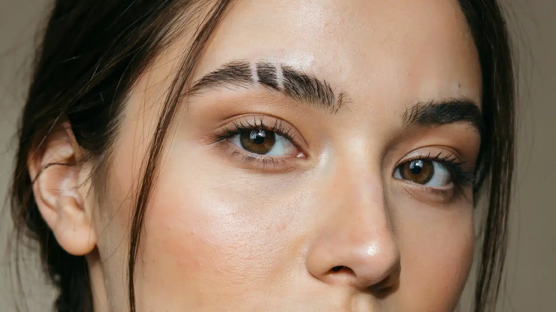 person with double eyebrow slits on thick groomed brows against a neutral background