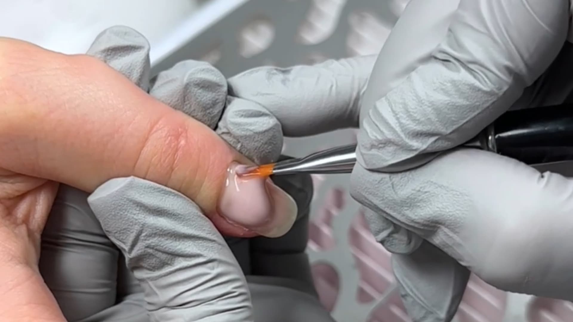 professional applying clear gel layer to natural nails with precision