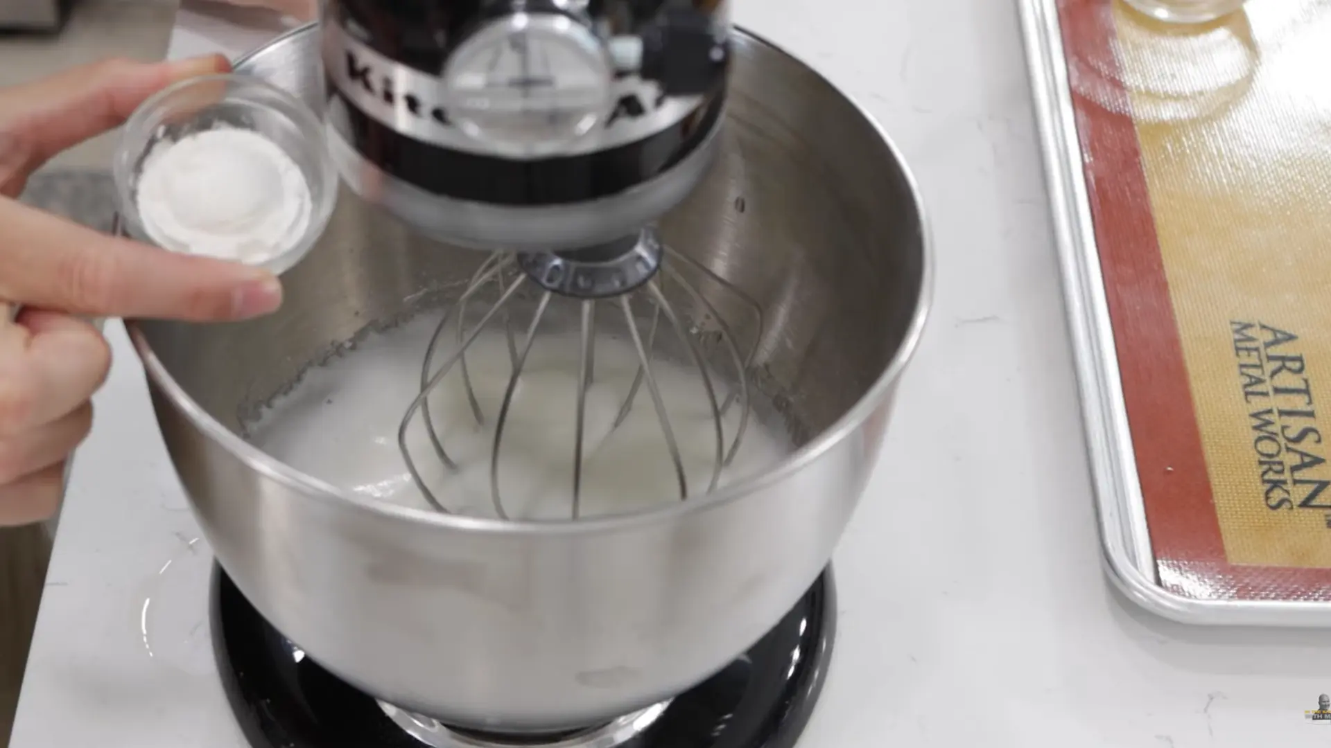 sifting cornstarch into egg white mixture to improve stability and prevent collapse after baking