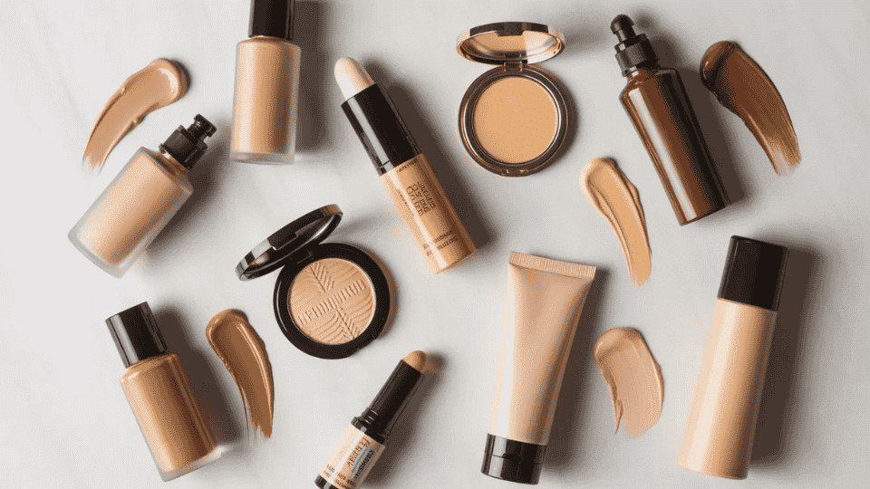 different types of foundation makeup products including liquid cream stick and powder foundation arranged on neutral background