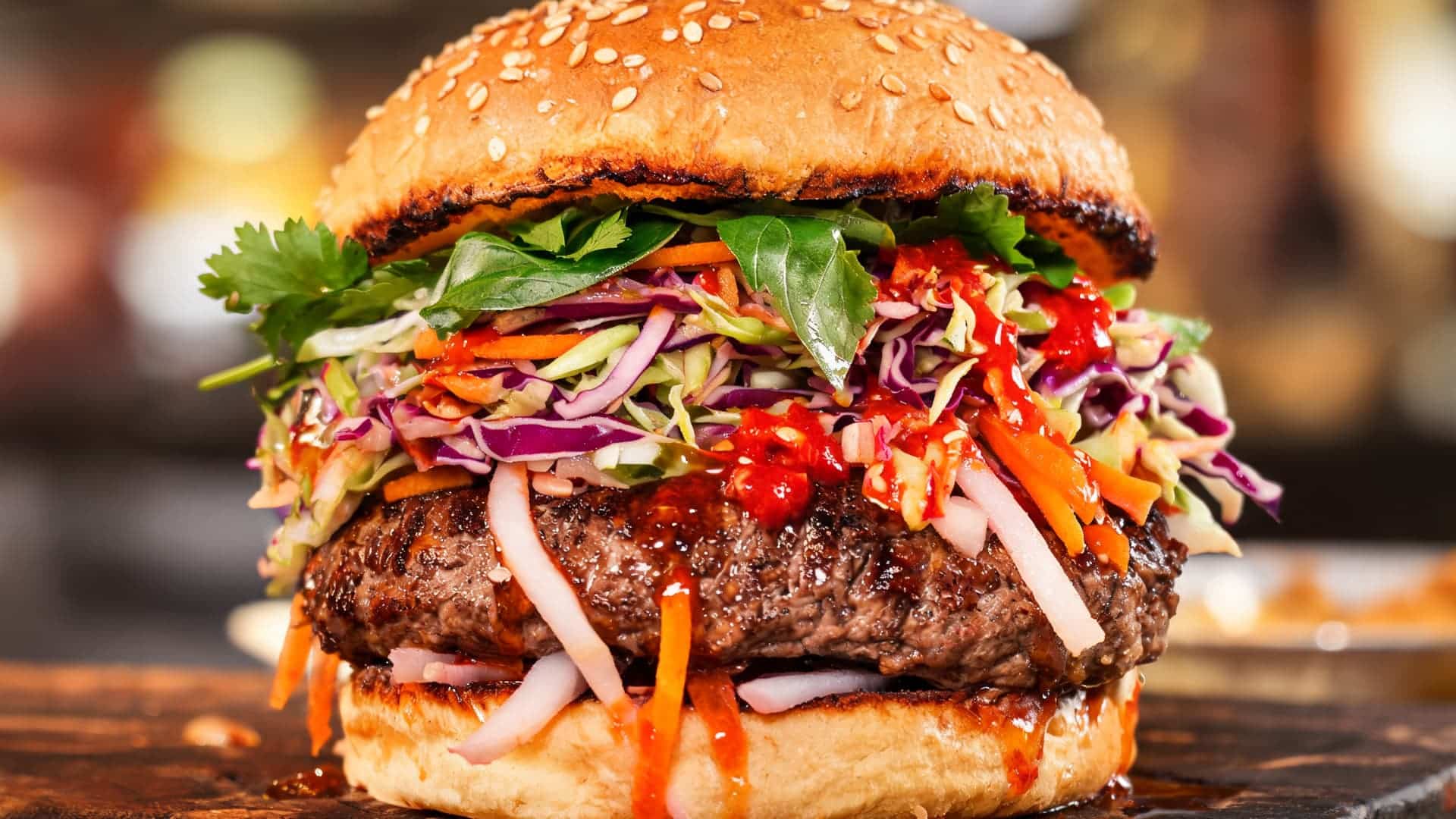fusion style burger with beef patty topped with colorful cabbage slaw herbs and spicy sauce on toasted bun close up realistic texture and vibrant colors