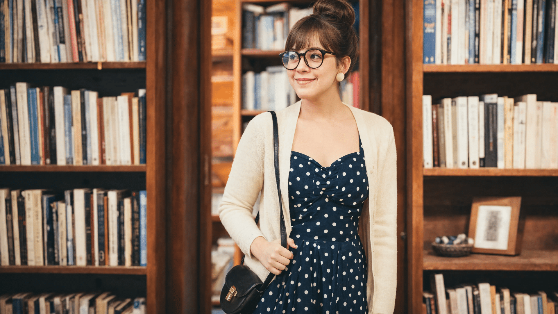 twee aesthetic fashion with polka dot dress, cardigan, retro glasses, and cozy bookstore background (1)