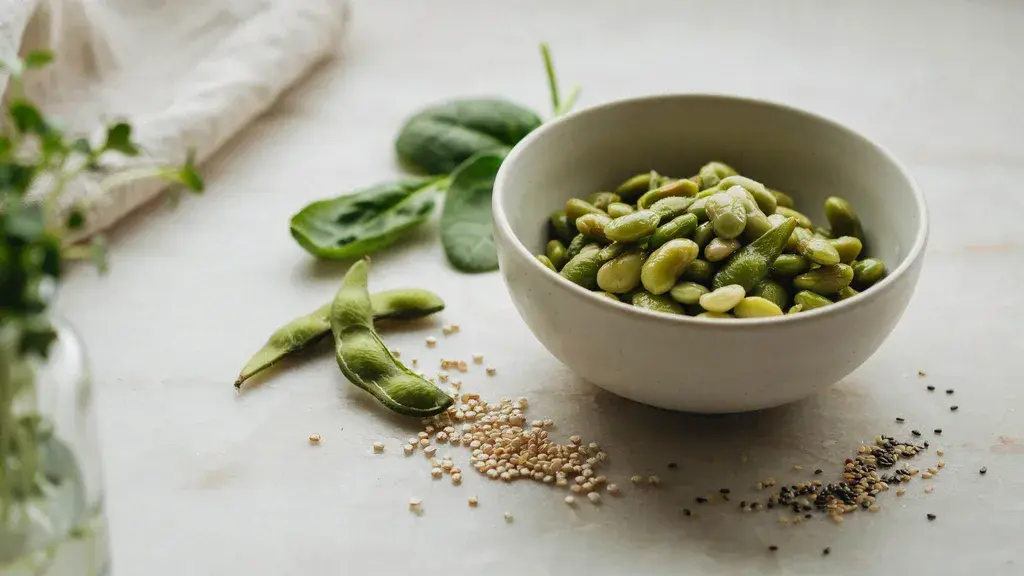 Bowl of shelled edamame with leafy greens grains and seeds creating a healthy nutrition focused food scene