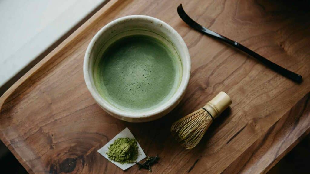 traditional matcha bowl with bamboo whisk and powder showing caffeine content