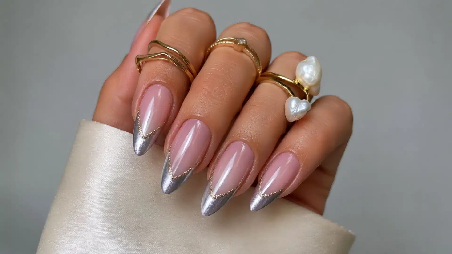 Almond nails with chrome silver French tips lined in gold glitter.