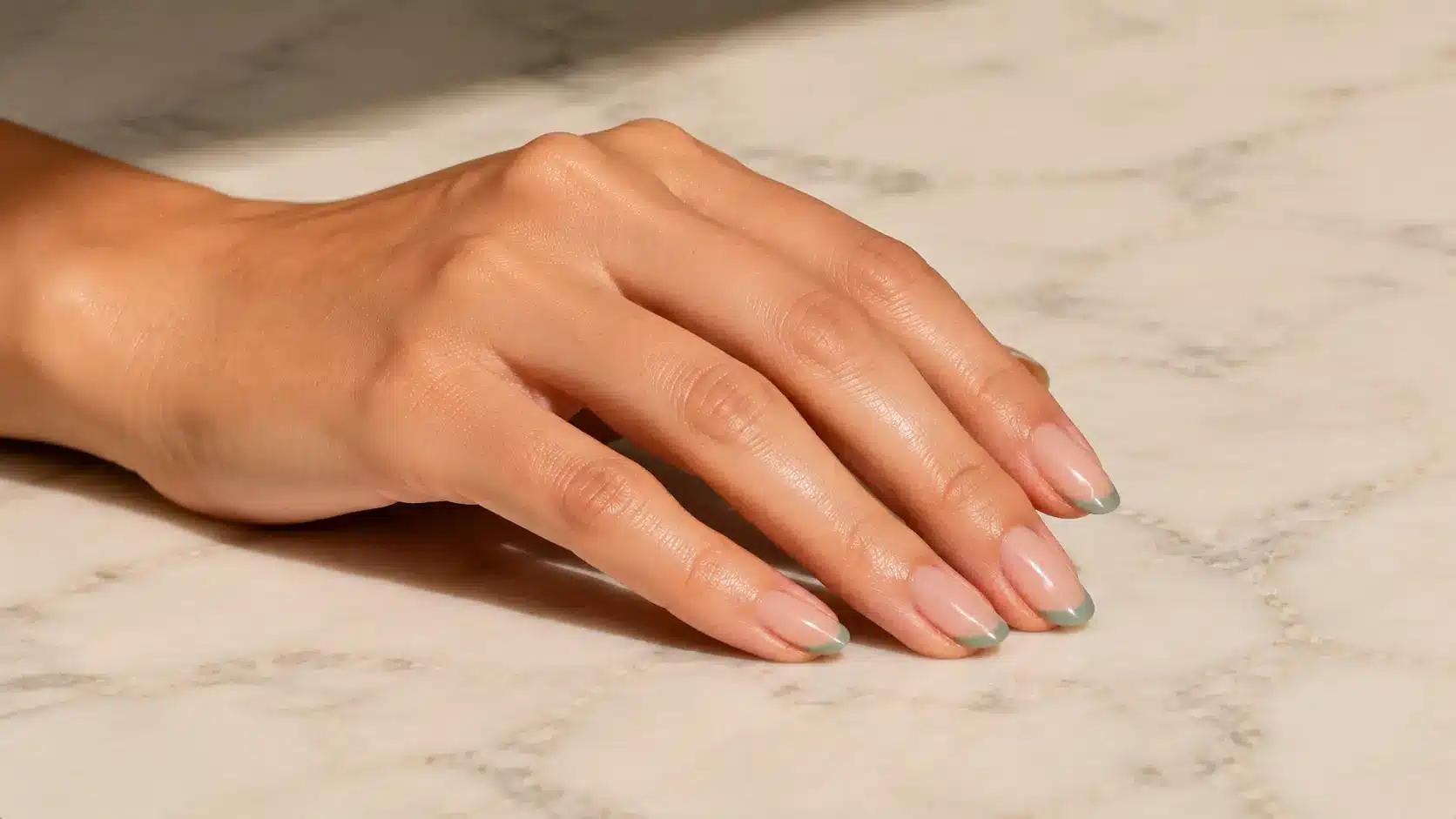 Geometric line nail design featuring glossy nude nails with minimal green angular tips for a simple nail art look