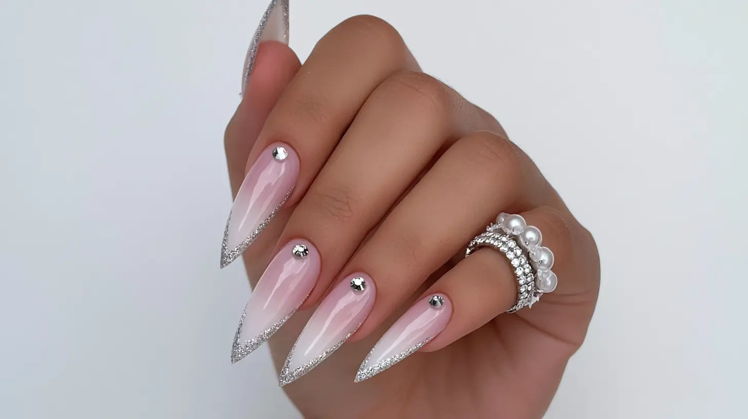 Long stiletto nails with pink ombre, silver glitter edges, and crystal gems.