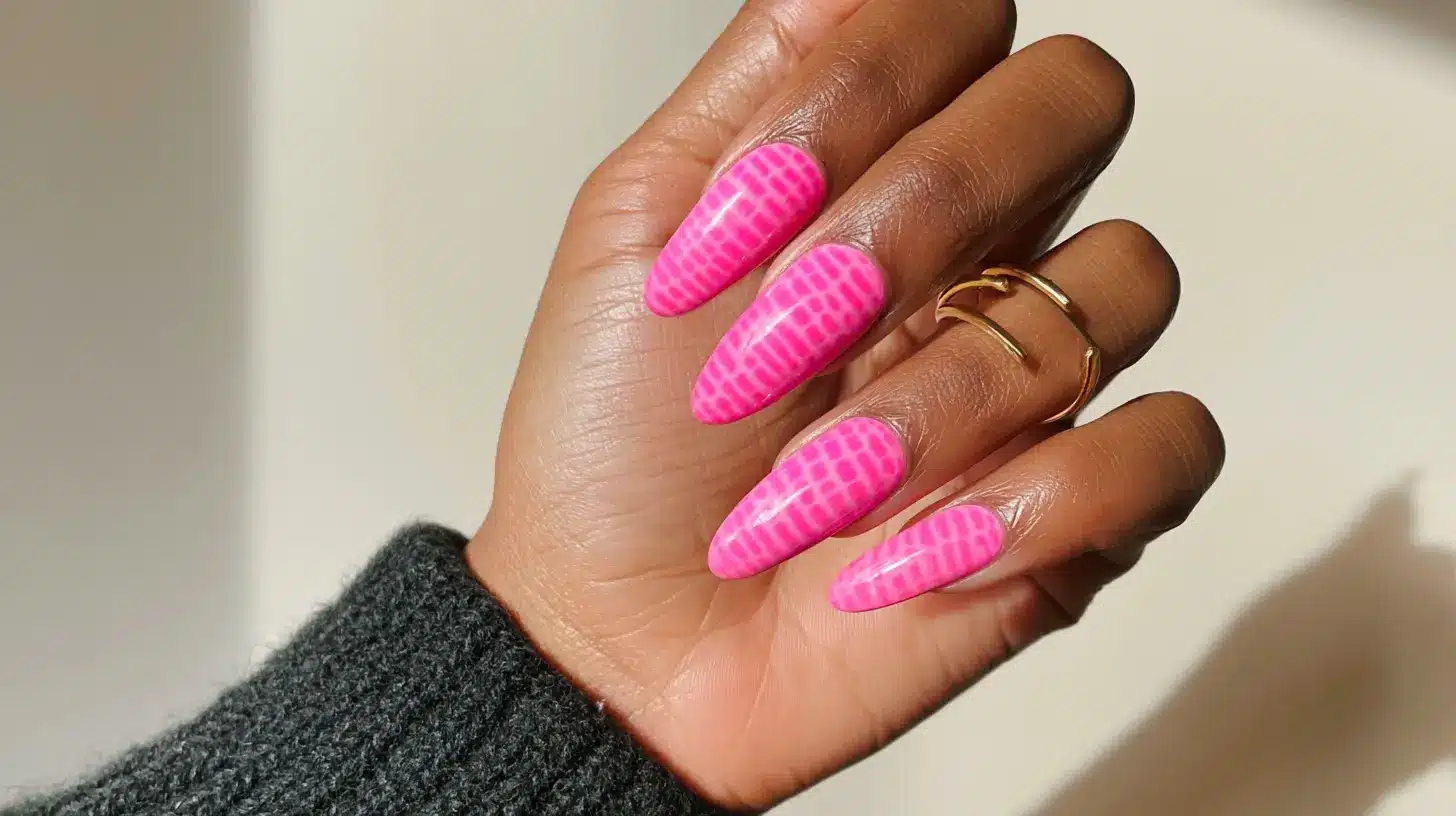 Bright pink crocodile print nail art on long almond-shaped glossy nails.